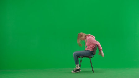 Portrait of victim on chroma key green screen background. Girl sitting on the chair with tied hands, scared face expression, screaming for help.の写真素材