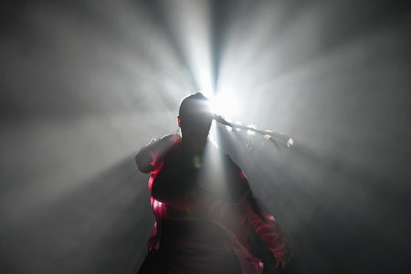 Silhouette of a girl dancing in a dark studio with smoke and back light. The dancer demonstrates...