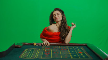 Gorgeous female in studio on chroma key green screen. Appealing woman in red dress sitting at the...