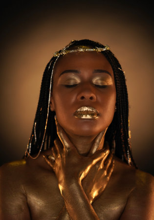 Portrait of an African-American woman with gold jewelry in her hair. The models arms, neck and...