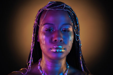 African American woman with gold jewelry in her hair. The models body covered with liquid gold...