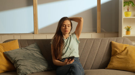 Portrait of young person in the room sitting on the couch. Woman in headphones listening to music on...
