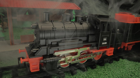 Childrens toy steam train in smoke. Close-up of model locomotive with steam. Atmosphere ideal for...