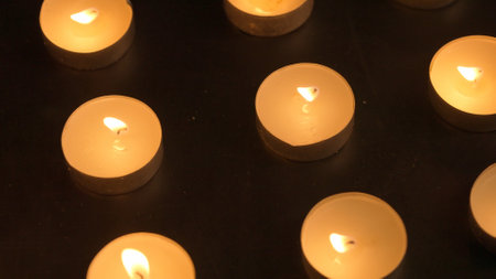 Burning candles. The candles burn against a black background and the flames move when the wind blows. The concept of a memorial day. Background for advertising and design projects.の写真素材