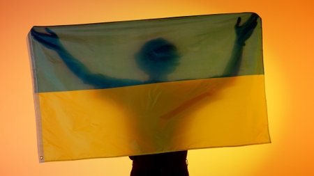 Person silhouette holding big flag against yellow background. Silhouette of man with national flag...