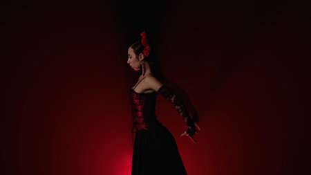 Woman dancing on black background with red light and smoke. Spanish dancer in red and black dress...