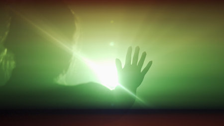 Silhouette in lighting concept. Female model against bright colored light on black smoky background in studio. Silhouette of a woman walking with her hands on rays of light.の写真素材