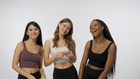 Portrait of young multiethnic models on white studio background close up. Group of three appealing multiracial girls hug and smile at the camera Multiethnic beauty concept.の写真素材