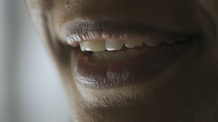 Macro shot of female model face. African American young woman macro shot of the face parts eyes and lips, model smiling shows teeth looks at the camera.の写真素材