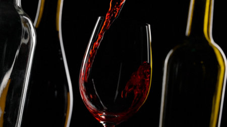 Elegant Red Wine Pouring into Glass Against Dark Background