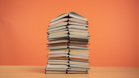 Colorful Pile of Books Against a Bright Orange Backgroundの写真素材