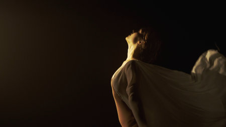 Young girl dancer in white chiffon on black background with emotional movements