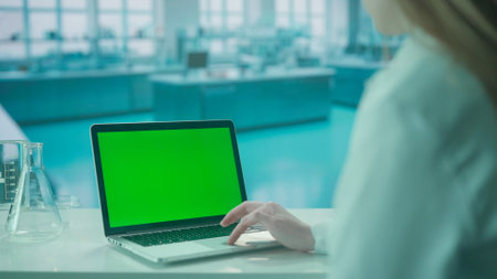 Laptop with Green Screen on Research Biochemistry lab Desk. Advertising area, workspace mock up.の写真素材