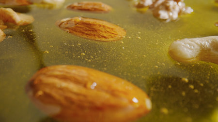 Sweet fresh golden honey with almonds, walnuts and hazelnuts in the thick syrup, close up shot.の写真素材