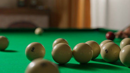 Close up shot of russian billiard green cloth table with white balls being hit by the red ball,...