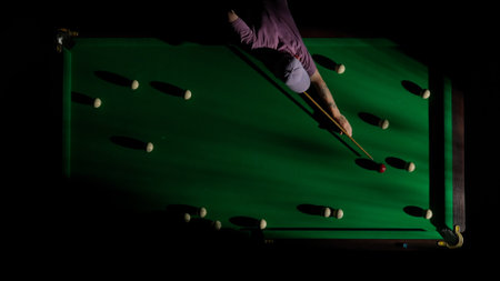 Top view shot of russian billiard green cloth table with red and white balls, person hitting the balls with cue.の写真素材