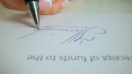 Close up shot of woman hand working with document, pen in female hand writing a personal signature...