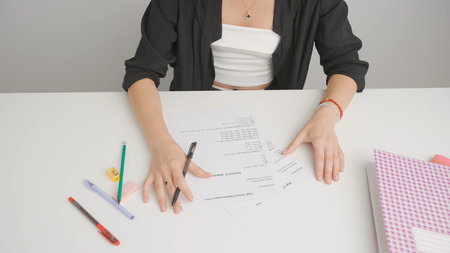 Female circles correct answers in standard exam test paper with black pen. Student filling up the...