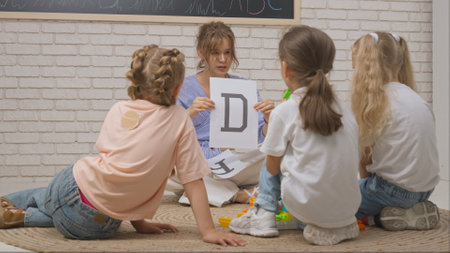 Young woman teacher and group of toddlers children doing creative tasks in developmental classes, learning alphabet. Children education concept.の写真素材