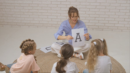 Young woman teacher and group of toddlers children doing creative tasks in developmental classes,...