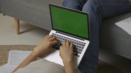 Focused adult man college student laying on the floor with laptop chroma key green screen doing...
