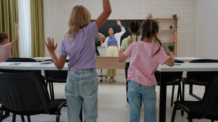 Junior school kids in classroom, woman teacher and children doing warm up stretching exercises during lesson. Elementary primary education.の写真素材