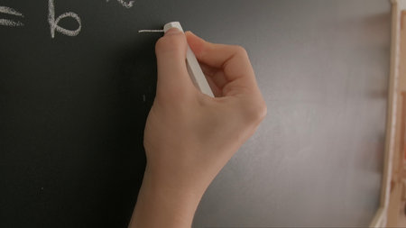Close up of woman hand writing programming text and formulas on chalkboard, professor writes on...