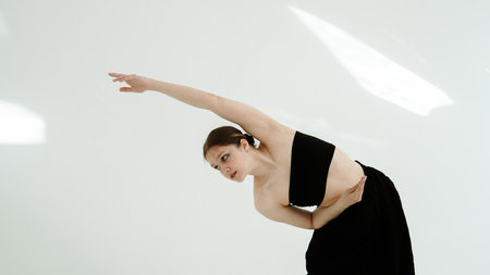 Young woman in black clothes dancing contemporary on white backgroundの写真素材