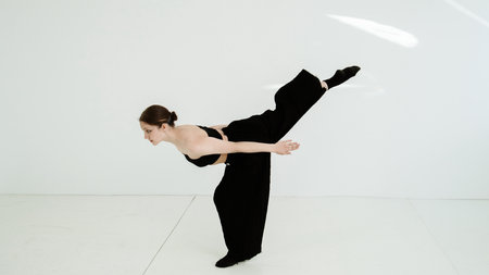 Young woman in black clothes dancing contemporary on white backgroundの写真素材