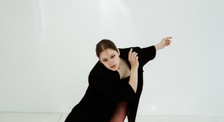 Young woman in black clothes dancing contemporary on white backgroundの写真素材