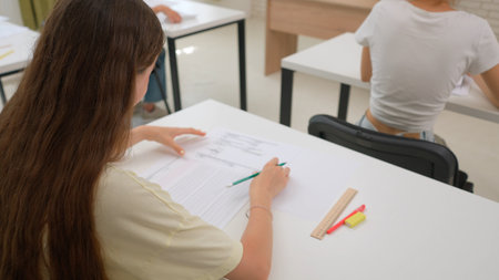 High school teenagers in classroom sitting at desks doing test, writing exam answering questions....