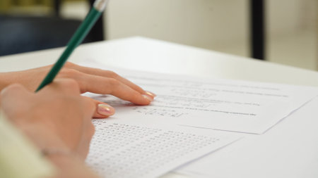 High school teenagers in classroom, close up shot girl writing math exam, solving task on paper sheet. Modern education concept.の写真素材