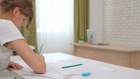High school teenagers in classroom, close up shot girl writing math exam, solving task on paper sheet. Modern education concept.の写真素材