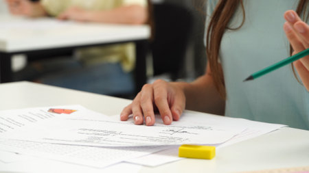 High school teenagers in classroom, close up shot girl writing math exam, solving task on paper sheet. Modern education concept.の写真素材