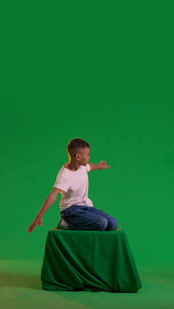 Playful schoolboy flying on a green box on a green screenの写真素材