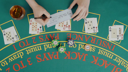 Gaming and casino payment concept. Top view of blackjack casino table, female player writing data on...