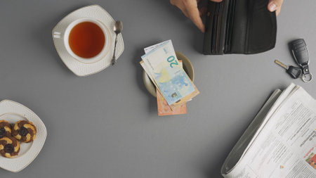 Top view of man hand paying bill at cafe or restaurant with cash, takes money banknotes from the wallet puts on the plate with receipt.の写真素材