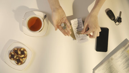 Top view of woman hand paying bill at cafe or restaurant with cash, puts euro coins on the plate with receipt.の写真素材