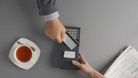 Top view of man hand paying bill at cafe or restaurant with bank credit card using portable...