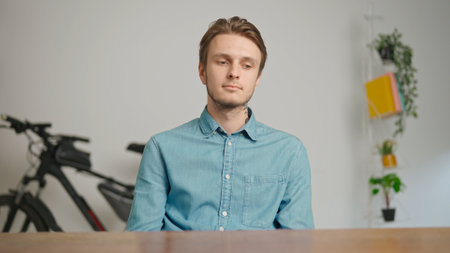 Man college student studying at home, sitting at desk, listening and watching lesson online on computer, nodding thinking. Modern online education.の写真素材