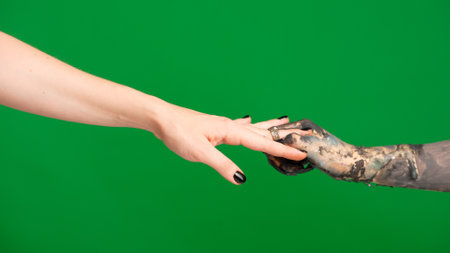 Creepy halloween monster hand in black paint with nails shows puts ring on human female finger, isolated on chroma key green screen background, workspace mockup.の写真素材