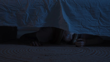 Scary ghost or monster hiding under bed in dark bedroom at night. Scary horror ghost peeking out from under the bed. Halloween Horror Concept.の写真素材