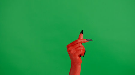 Creepy halloween devil monster hand in red paint with black nails shows finger heart sign, isolated on chroma key green screen background, workspace mockup.の写真素材