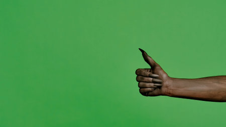 Creepy halloween monster hand in black paint with nails shows like thumb up sign, isolated on chroma...