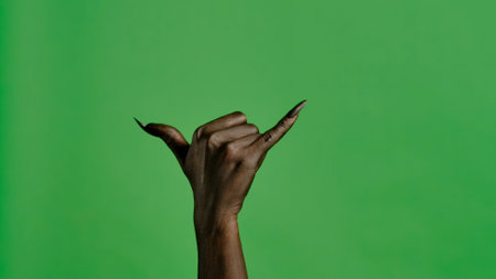 Creepy halloween monster hand in black paint with nails shows call me a gesture, isolated on chroma key green screen background, workspace mockup.の写真素材