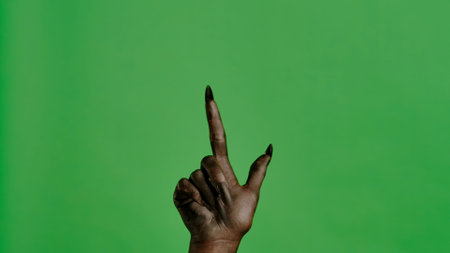 Creepy halloween devil monster hand in black paint with nails pointing finger up, isolated on chroma key green screen background, workspace mockup.の写真素材