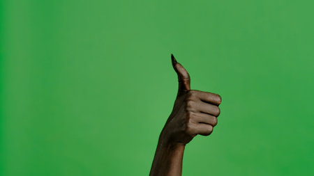 Creepy halloween devil monster hand in black paint with nails shows like thumb up sign, isolated on chroma key green screen background, workspace mockup.の写真素材