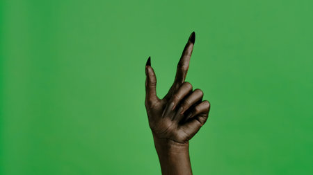 Creepy halloween devil monster hand in black paint with nails pointing finger up, isolated on chroma key green screen background, workspace mockup.の写真素材