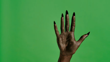 Creepy halloween devil monster hand in black paint with nails shows open palm, isolated on chroma key green screen background, workspace mockup.の写真素材