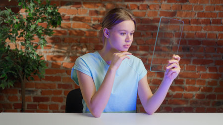 Female holding innovative futuristic tablet with transparent glass screen and watching media, with advertisement empty place to insert infographic animation.の写真素材